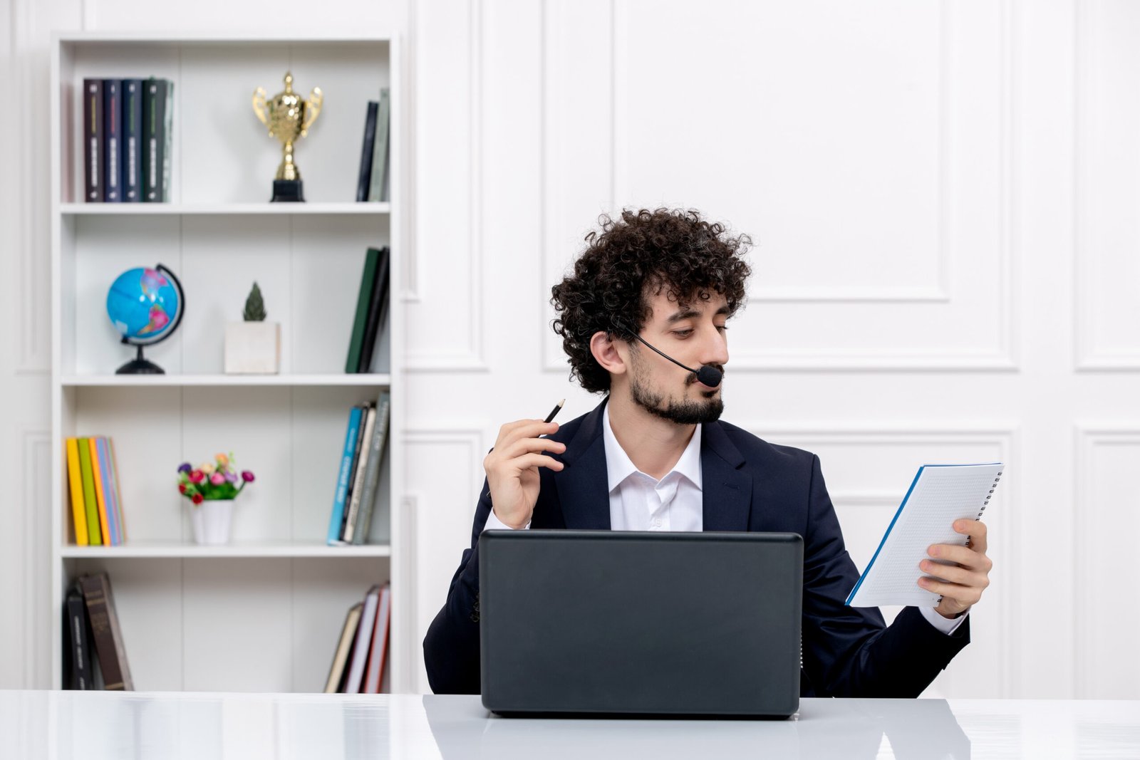 customer-service-handsome-curly-man-office-suit-with-computer-headset-reading-notes